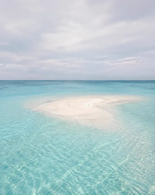 A small white sandbank surrounded by clear shallow lagoon water