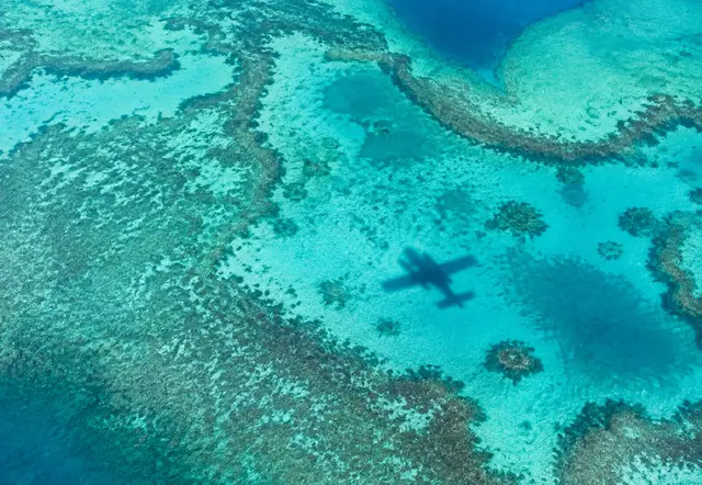 Aerial view of reef patterns with the shadow of a seaplane on the water