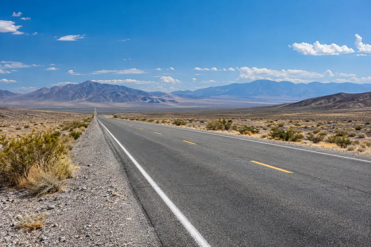 An empty public desert highway surrounded by Nevada scenery