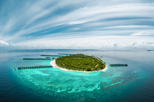 Aerial view of Siyam World Maldives, with the island, beaches, and overwater villas surrounded by the lagoon. Photo: Sun Siyam Resorts.